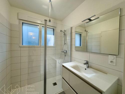 une salle de bain blanche avec un lavabo et un miroir dans l'établissement Vieux Doëlan, à Clohars-Carnoët