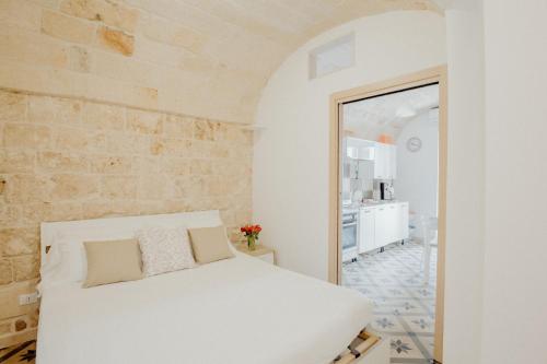 a bedroom with a white bed and a brick wall at Palazzo Pezzolla Apartments in Monopoli