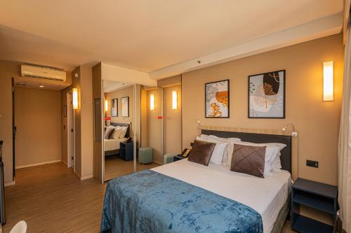 a hotel room with a large bed and a hallway at APS - Alpha Stay By Anora Spaces in Barueri