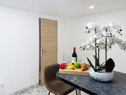 - une table avec un vase de fleurs et des bouteilles de vin dans l'établissement Garden Appartement- Paris - Blanc Mesnil, au Blanc-Mesnil