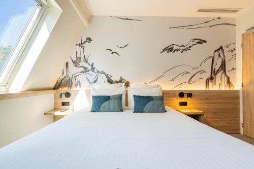 a bedroom with a large bed with blue pillows at GREEN PARK HOTEL PARIS in Paris