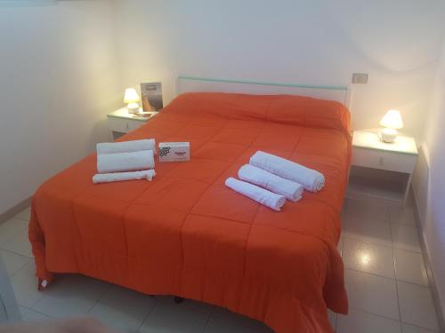 a bedroom with a orange bed with towels on it at Bilocali Baia Verde in Baia Verde