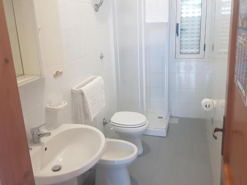 a white bathroom with a toilet and a sink at Bilocali Baia Verde in Baia Verde