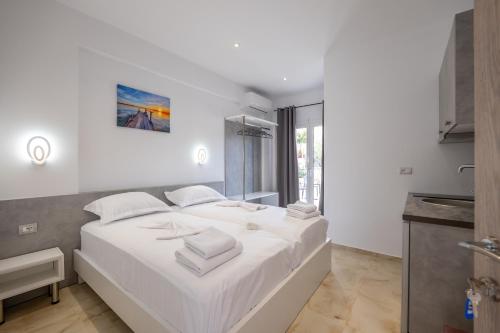 a white bedroom with a large bed with towels on it at Vila Ali in Sarandë