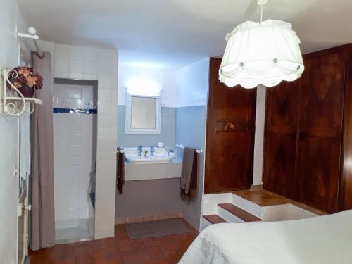 a bathroom with a tub and a sink and a chandelier at La Lavande in La Robine