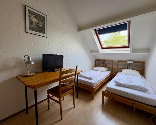 a room with two beds and a desk with a computer at Kustverhuur, Park Schoneveld Duinroos 131 in Breskens