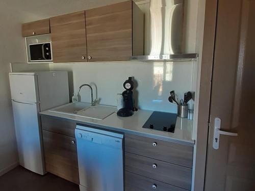 une petite cuisine avec un évier et un réfrigérateur dans l'établissement Cammari's logement pour 6 personnes proche plage et port, à Gruissan