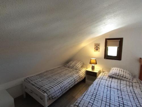 une chambre avec deux lits et un miroir au mur dans l'établissement Cammari's logement pour 6 personnes proche plage et port, à Gruissan