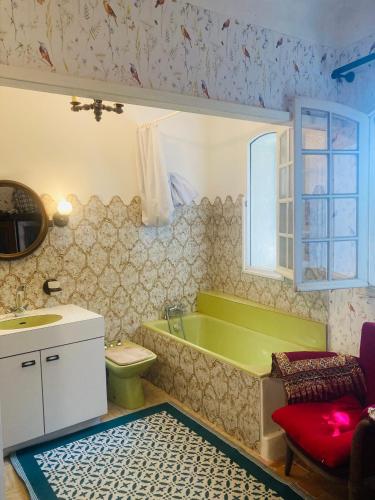La salle de bains est pourvue d'une baignoire verte, de toilettes et d'un lavabo. dans l'établissement Maison de famille en Provence, à Rognes