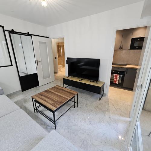 un salon avec une table basse et une télévision à écran plat dans l'établissement Idéal Central Calme Cosy Chaleureux Zen Appartement Mignon, à Nice