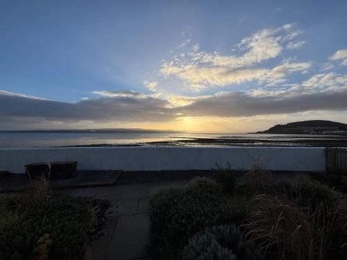 a view of the ocean from a patio with the sunset at SEASIDE HOUSE 12 Shore Street, Avoch IV9 8QD in Avoch