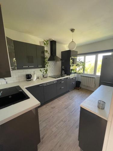 une cuisine avec des armoires noires et un plancher en bois dans l'établissement Le petit cocon à la campagne, à Beuzevillette