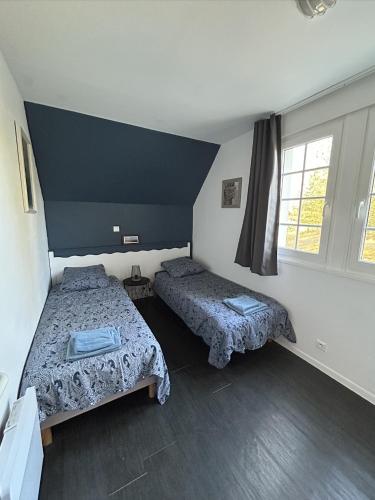 une chambre avec deux lits et deux fenêtres dans l'établissement H02, à Fort-Mahon-Plage