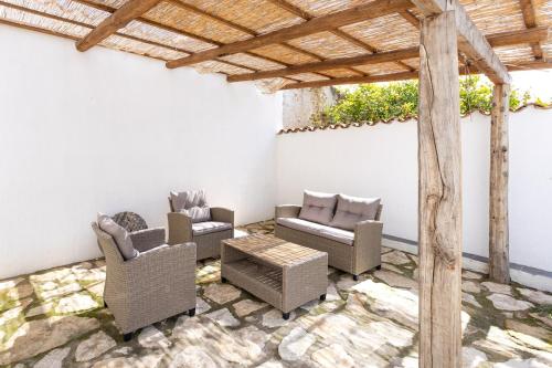 a patio with couches and chairs and a wooden pergola at Way to the sea - Home with garden & hot tub in Càbras