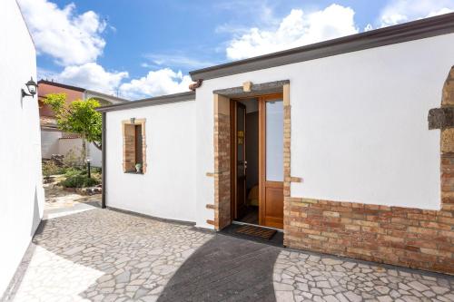 a white house with a door and a brick wall at Way to the sea - Home with garden & hot tub in Càbras
