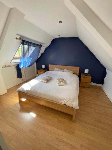 une chambre avec un grand lit avec un mur bleu dans l'établissement Le petit cocon à la campagne, à Beuzevillette
