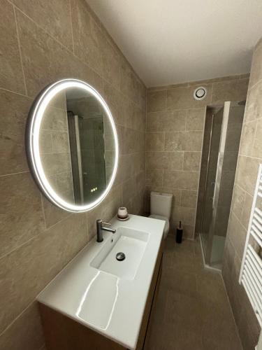 une salle de bain avec un lavabo blanc et un miroir dans l'établissement Le Petra Paoli - Appt climatisé avec piscine, à LʼÎle-Rousse