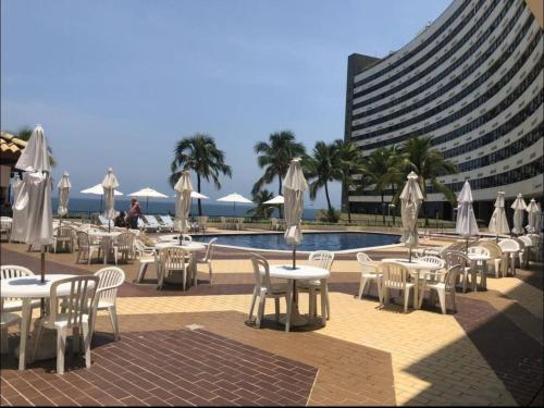 a group of tables and chairs next to a pool at Ondina Apart Hotel 02 quartos Vista Mar in Salvador