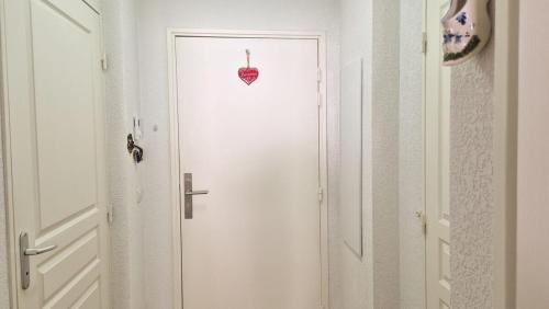une porte blanche avec une pomme rouge dessus dans l'établissement Studio cosy au cœur de la station avec piscine, à Péone