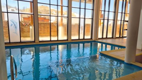 - une grande piscine dans un bâtiment doté de fenêtres dans l'établissement Studio cosy au cœur de la station avec piscine, à Péone