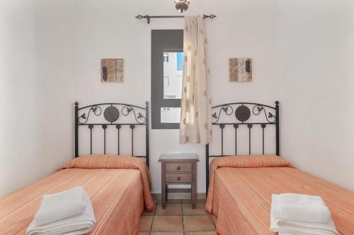 two beds with orange sheets in a white room at Preciosa casa en Conil in Conil de la Frontera