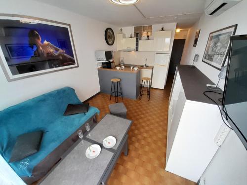 un salon avec un canapé bleu et une télévision dans l'établissement Appartement Rosy Village Naturiste, au Cap d'Agde