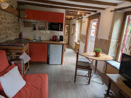 a kitchen with red cabinets and a table in a room at Gîte rustique au cœur de la nature in Soubrebost