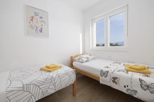 two beds in a white room with a window at Apartman MORE Živogošće in Živogošće
