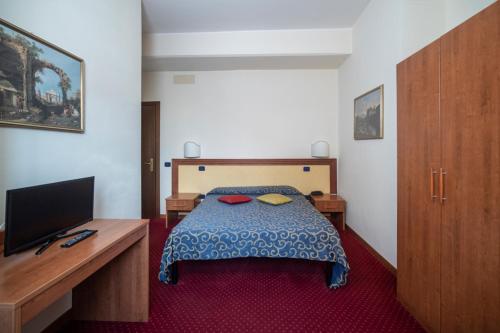a bedroom with a bed and a desk with a television at Hotel Italia & Lombardi in Montefiascone
