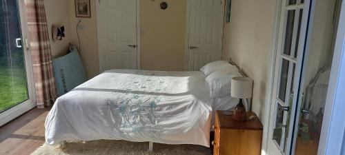 a bedroom with a bed with a white comforter at Bali Hi Cliff Cottage-Sleeps 2-Hot Tub-5MinBeach in Sheerness