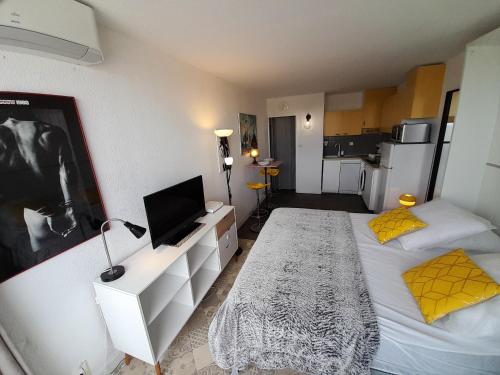 une petite chambre avec deux lits et une télévision dans l'établissement Appartement Relax Village Naturiste Héliopolis, au Cap d'Agde