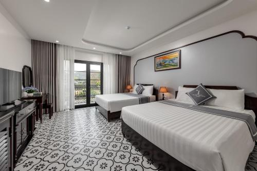 a hotel room with two beds and a television at Tam Coc Lighthouse Hotel in Ninh Binh