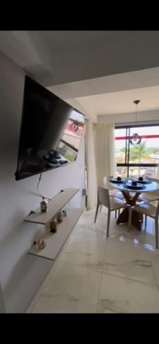 a living room with a table and a television on a wall at Tambaú Mar Hotel in João Pessoa