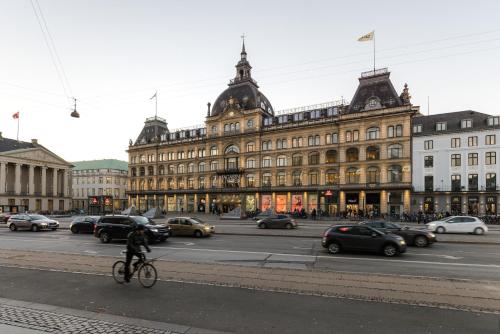 a person riding a bike in front of a large building at Perfect Apartments in Superb Location by Strøget, the Metro & Attractions in Copenhagen