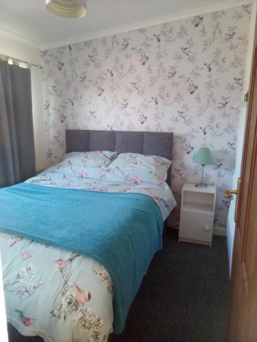 a bedroom with a bed with a floral wallpaper at 2 bed seaside holiday Chalet in Mablethorpe