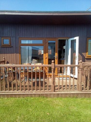 a house with a deck with a table and chairs at 2 bed seaside holiday Chalet in Mablethorpe