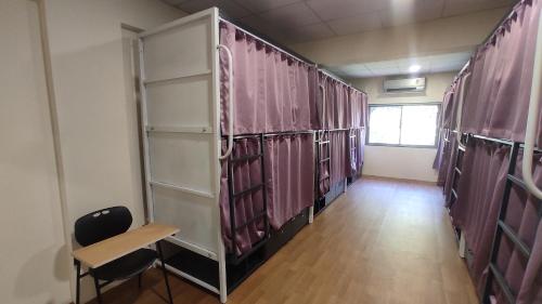 a locker room with pink curtains and a table and chairs at Hostells in Pune