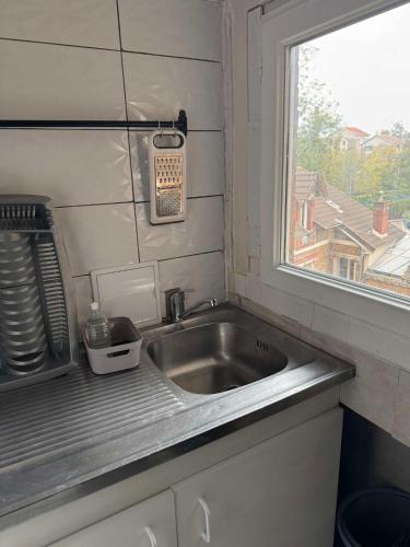 d'un évier dans une cuisine avec une fenêtre. dans l'établissement Appartement RIS ORANGIS, à Ris-Orangis