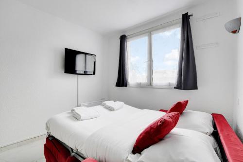 une chambre avec un lit avec des oreillers rouges et une fenêtre dans l'établissement Nice & Quiet Studio - Saint Denis, à Saint-Denis