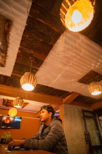 a man sitting at a table in a room with lights at Hotel Juju in Pokhara