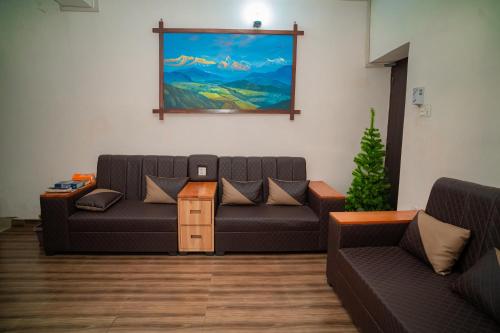 a living room with two couches and a painting on the wall at Hotel Juju in Pokhara