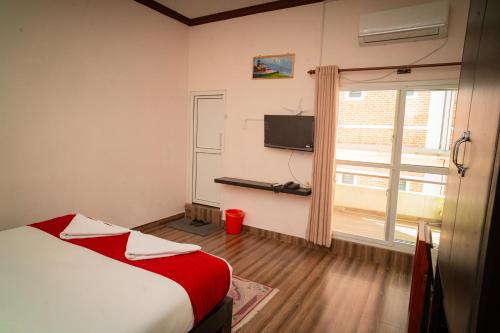a bedroom with a bed and a window with a television at Hotel Juju in Pokhara