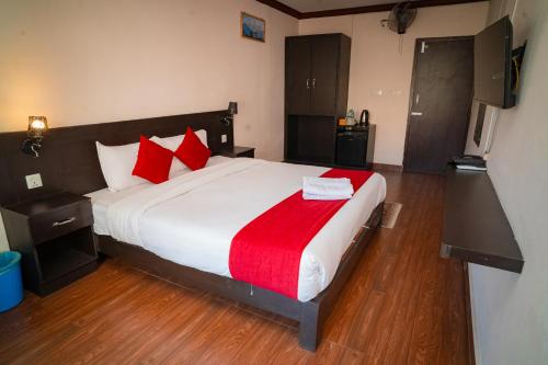 a bedroom with a large white bed with red pillows at Hotel Juju in Pokhara