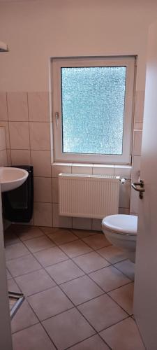 a bathroom with a toilet and a window at Brauereigasthof Hösl Pension in Mitterteich