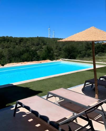 - une piscine avec une table, un parasol et des chaises dans l'établissement Le Loft, à Esparron