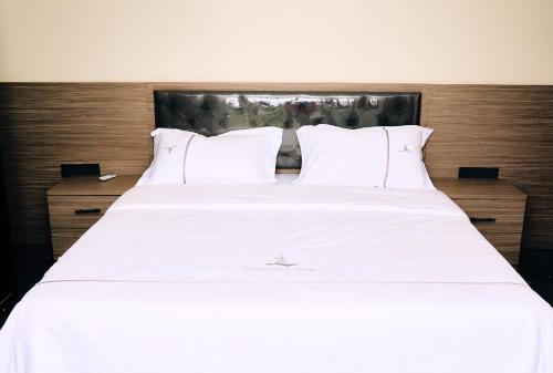 1 cama blanca grande con sábanas y almohadas blancas en Modern 2 bedroom apartments in Kigali, en Kigali