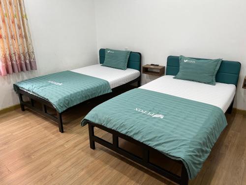 two beds in a room with green and white sheets at PUPON Homestay and Coffee in Quang Ngai
