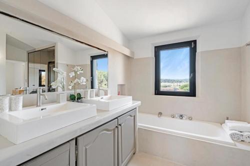La salle de bains est pourvue de 2 lavabos, d'une baignoire et d'un grand miroir. dans l'établissement Luxueuse villa vue vignes avec piscine et terrain de petanque, à Gassin