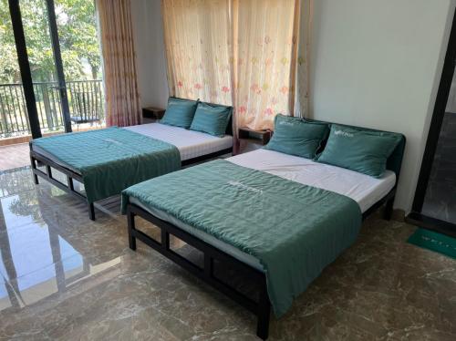 two beds in a room with green sheets at PUPON Homestay and Coffee in Quang Ngai