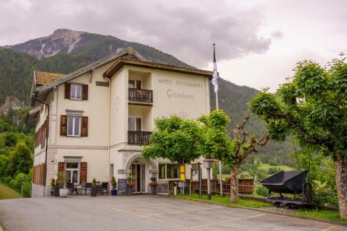 a large white building with a mountain in the background at Hotel Grischuna Filisur in Filisur